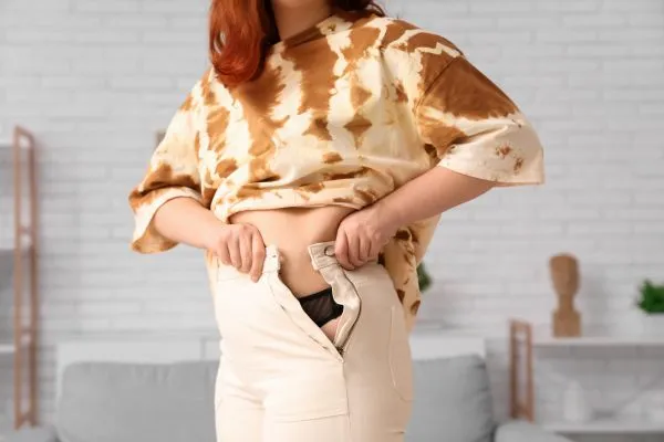 Image of woman trying to do her trousers up after pregnancy weight gain Newcastle under Lyme